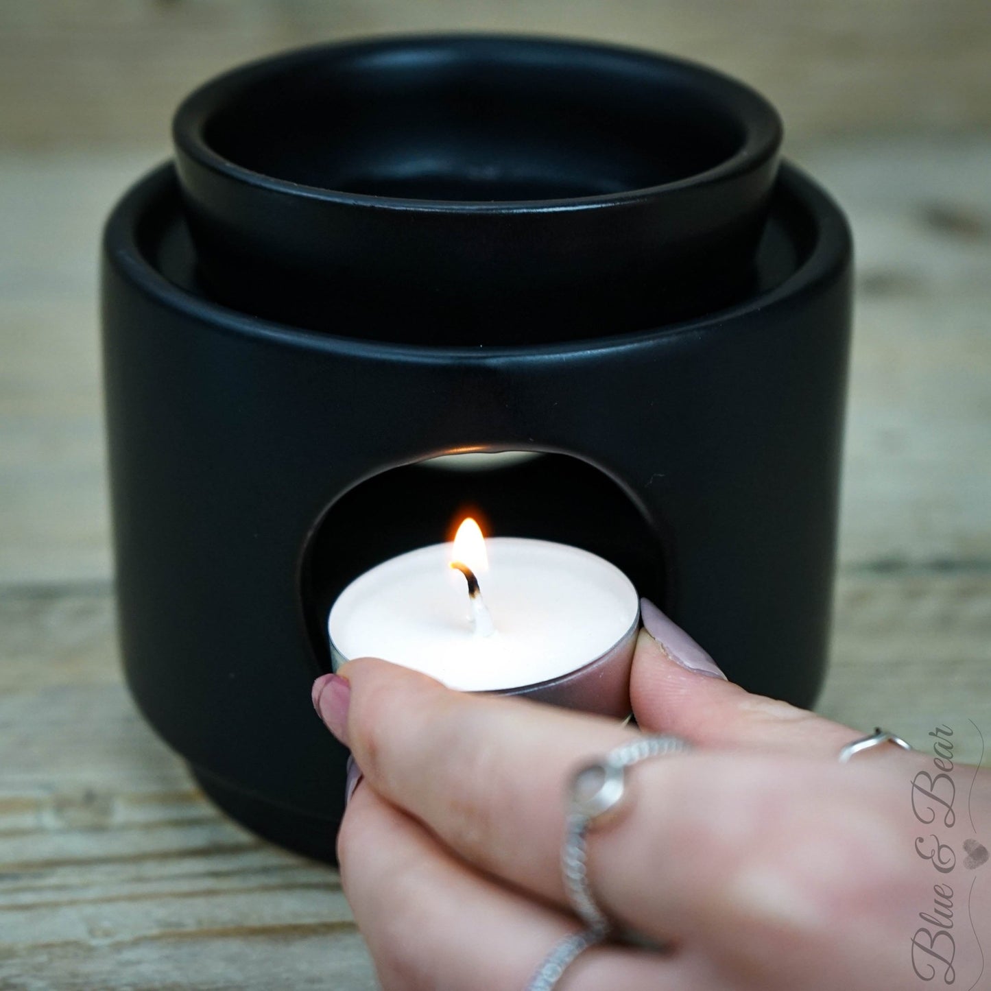 Placing a lit Natural Wax Tea Light inside a Blue & Bear Ceramic Wax & Oil Burner, ready to melt our Botanical Palettes or Pure Essential Oils.