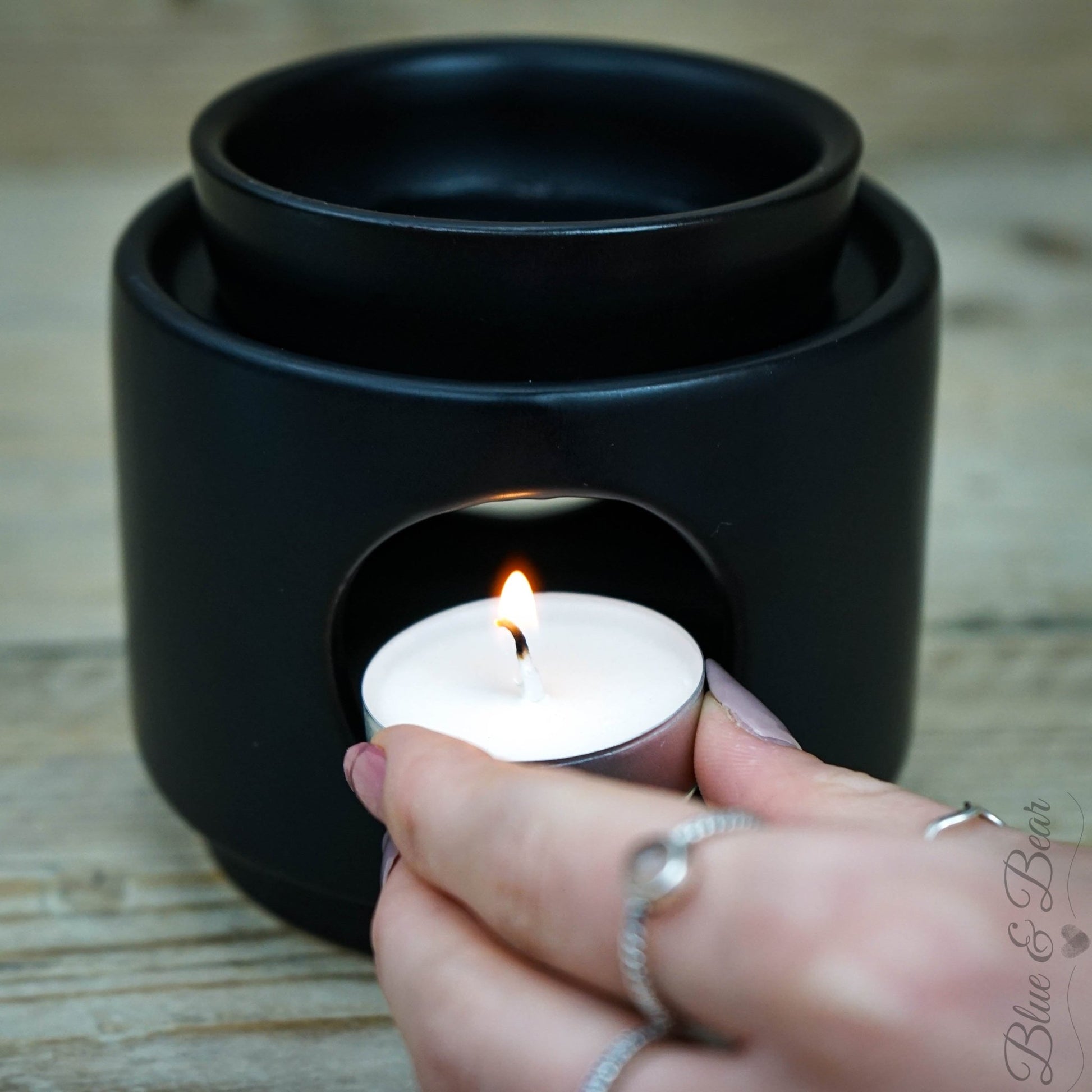 Placing a lit Natural Wax Tea Light inside a Blue & Bear Ceramic Wax & Oil Burner, ready to melt our Botanical Palettes or Pure Essential Oils.
