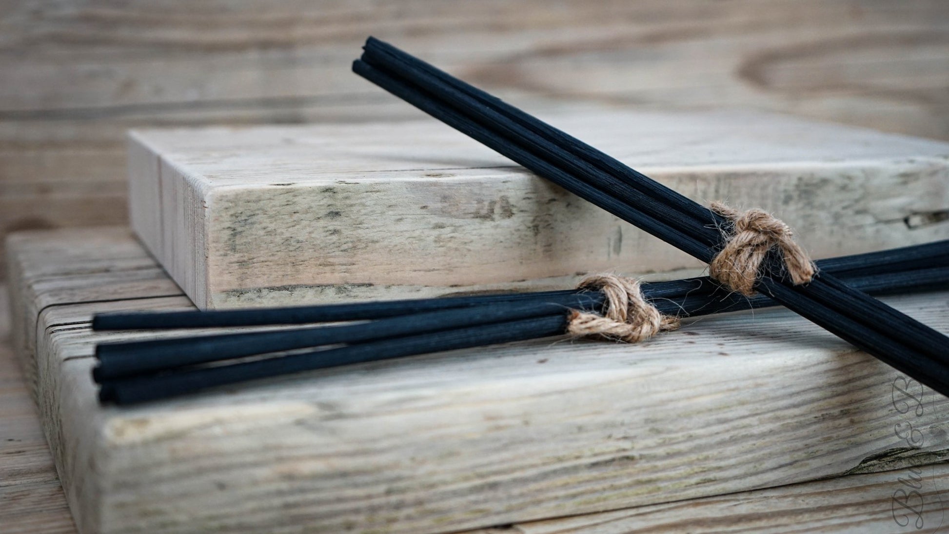 Two bundles of six thick black rattan reeds tied with jute string, resting pon one another.  The perfect replacement to refresh your Blue & Bear  Essential Oil Reed Diffuser.