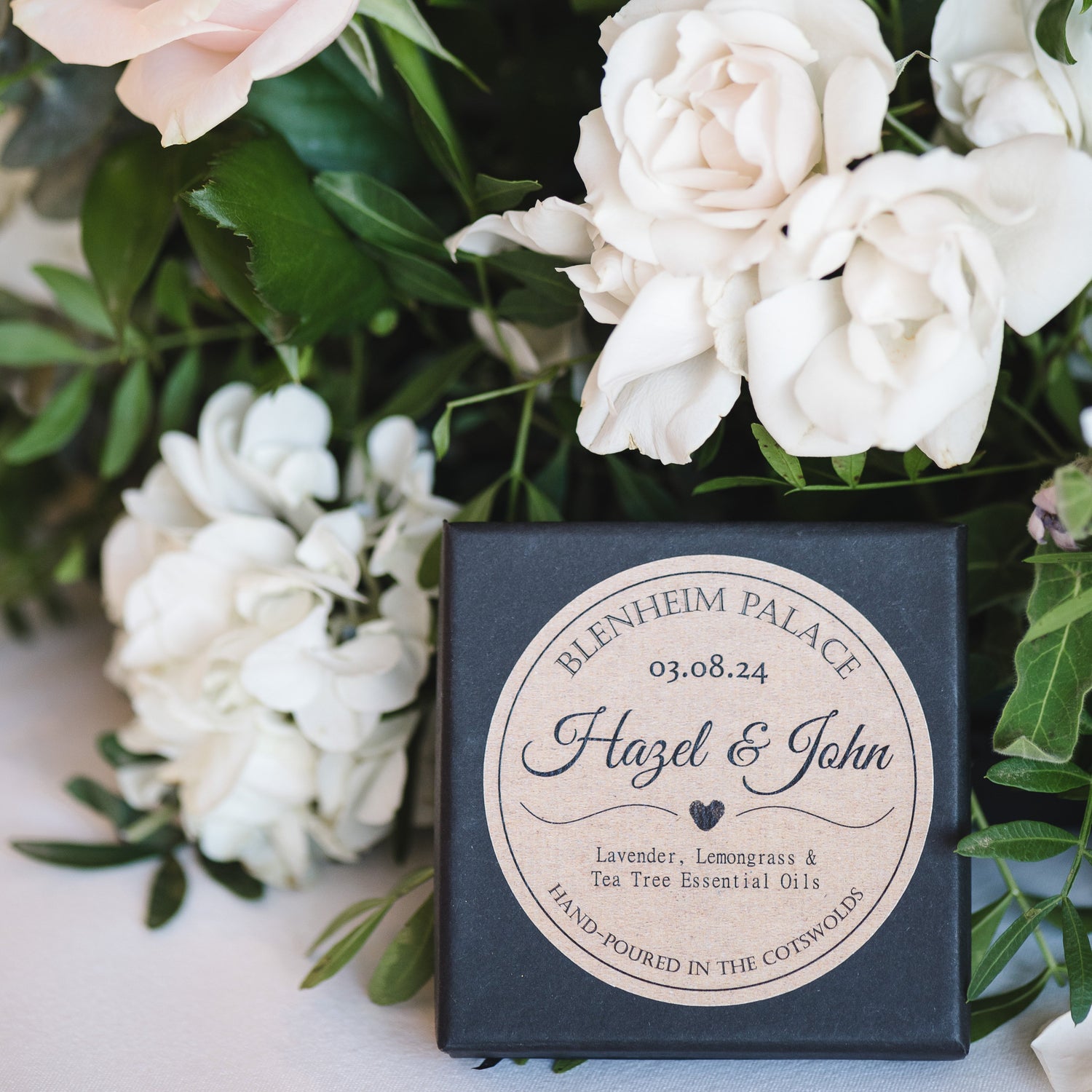 A bespoke wedding favour botanical palette from Blue & Bear, nestled against a bouquet of white roses