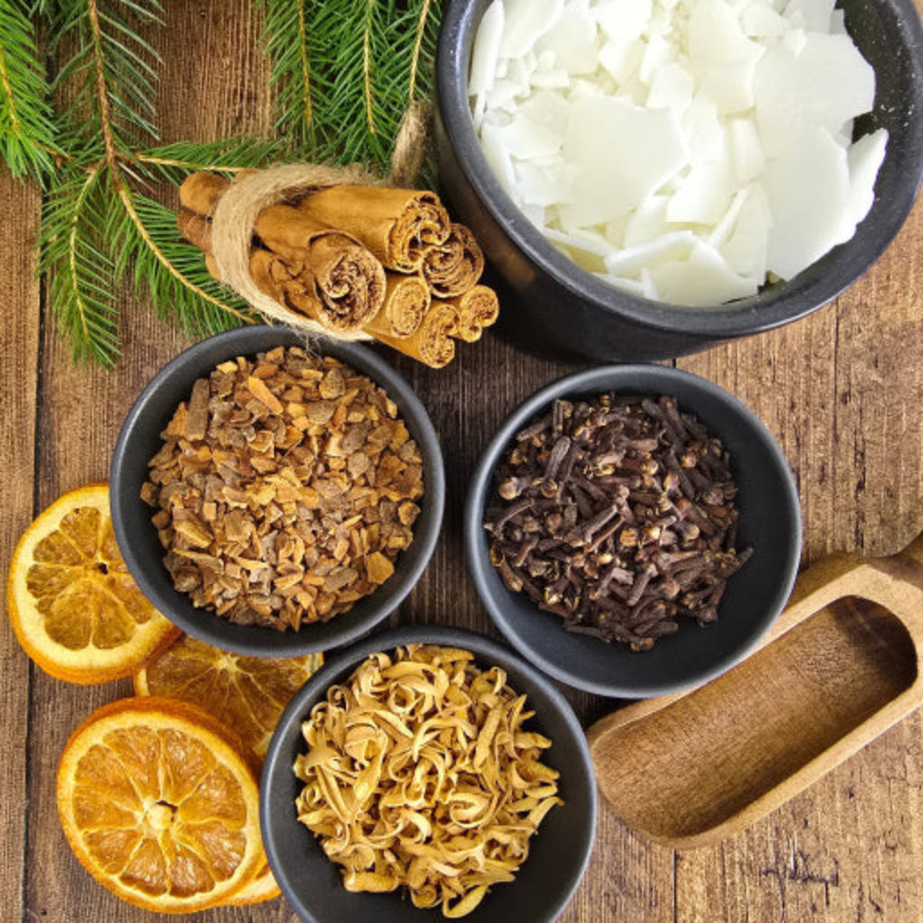 Botanicals and soy way in bowls on a wooden surface with oranges and pine branches.  Blue & Bear Christingle the new limited-edition scent 